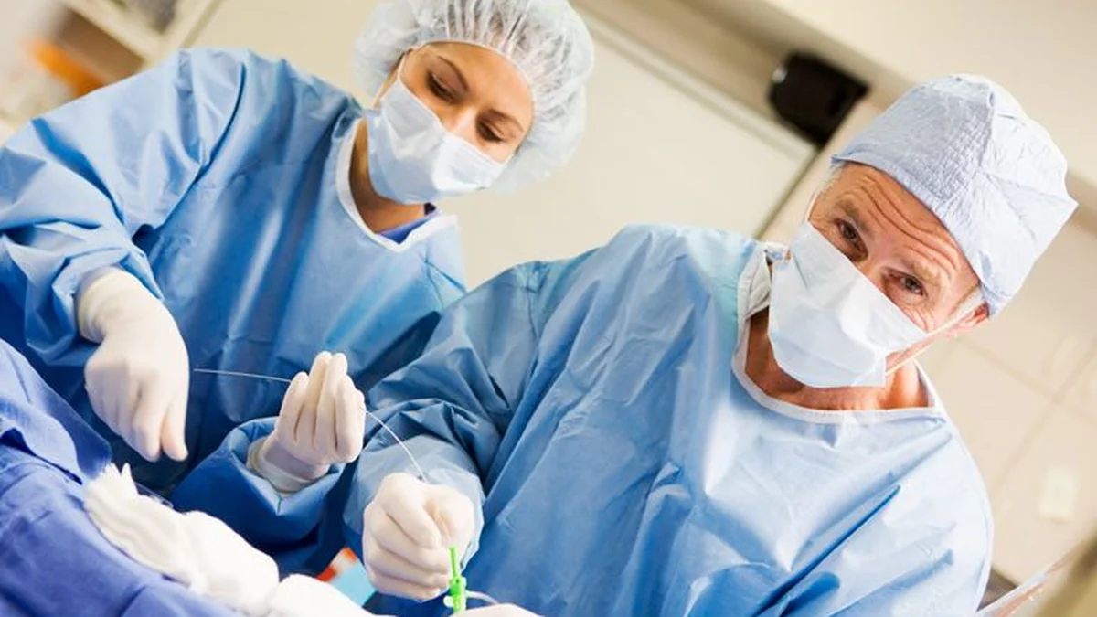 Anaesthesia team preparing a line at the head of the operating table